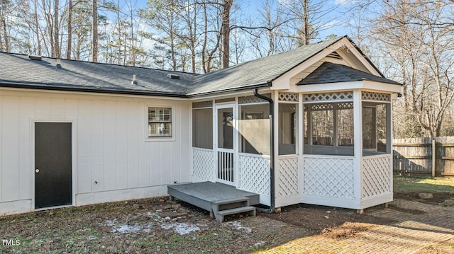 view of outdoor structure featuring a sunroom and fence