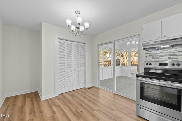 kitchen featuring tasteful backsplash, under cabinet range hood, light wood-style flooring, stainless steel electric range, and a notable chandelier