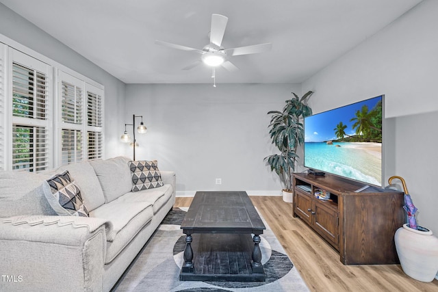 living area with baseboards, light wood-style floors, and ceiling fan