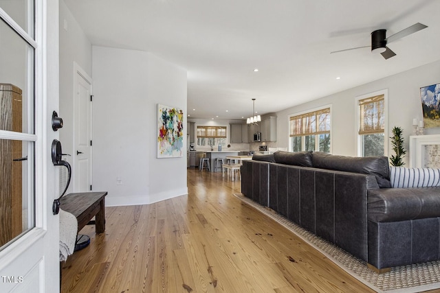 living room with ceiling fan and light hardwood / wood-style flooring