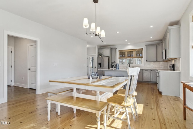 dining space with sink, a chandelier, and light hardwood / wood-style floors