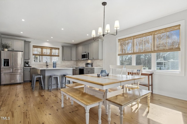 dining area with sink, a wealth of natural light, a notable chandelier, and light hardwood / wood-style floors