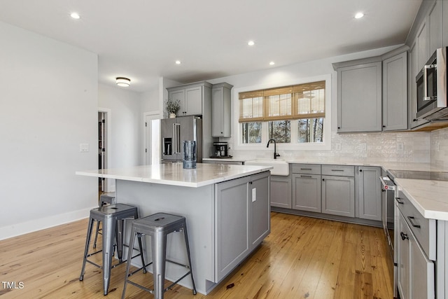 kitchen with sink, gray cabinetry, premium appliances, a kitchen breakfast bar, and a kitchen island