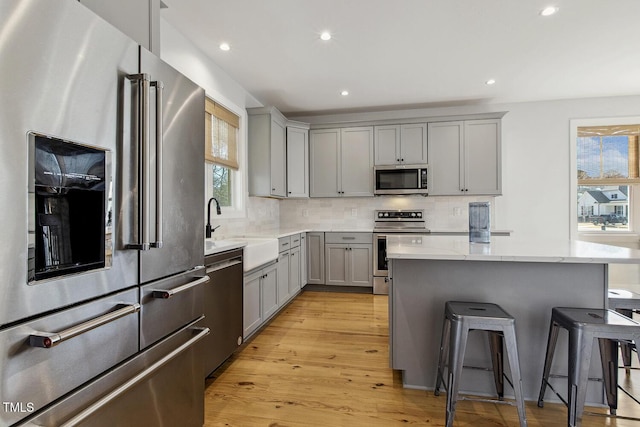 kitchen featuring sink, gray cabinets, a breakfast bar, appliances with stainless steel finishes, and a center island