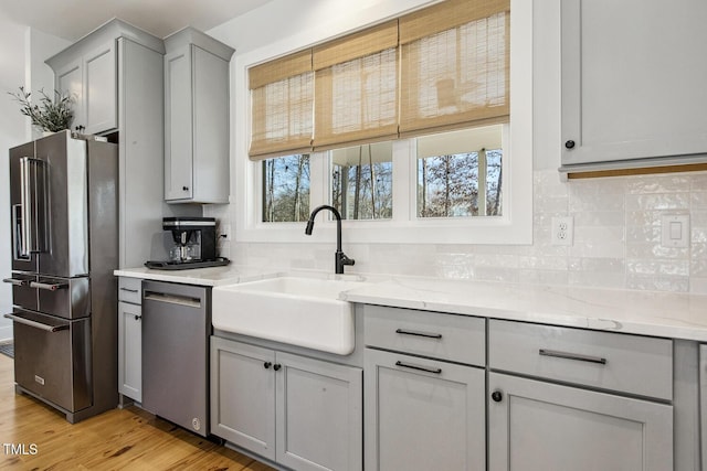 kitchen with gray cabinetry, sink, decorative backsplash, and stainless steel appliances