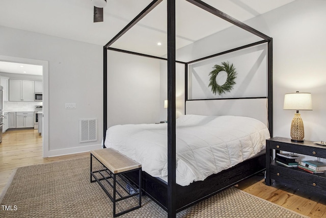 bedroom featuring stainless steel refrigerator and light hardwood / wood-style floors