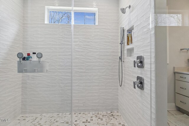 bathroom featuring a tile shower and vanity