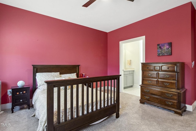 bedroom with ceiling fan, light carpet, and ensuite bath