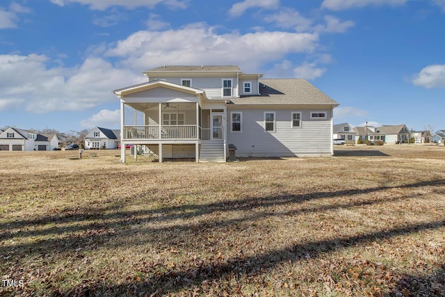 rear view of property featuring a porch, a sunroom, and a yard