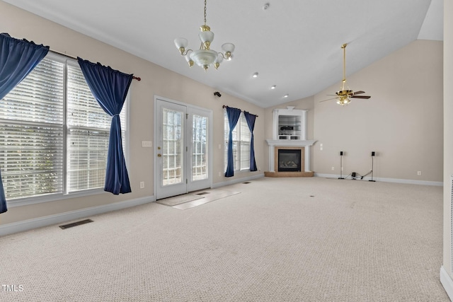 unfurnished living room featuring ceiling fan with notable chandelier, vaulted ceiling, and carpet