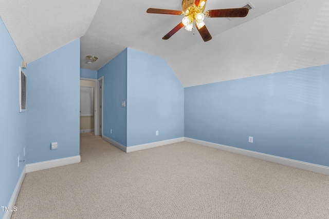 additional living space with ceiling fan, light colored carpet, vaulted ceiling, and a textured ceiling