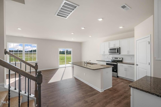 kitchen with white cabinetry, a center island with sink, stainless steel appliances, and dark stone countertops