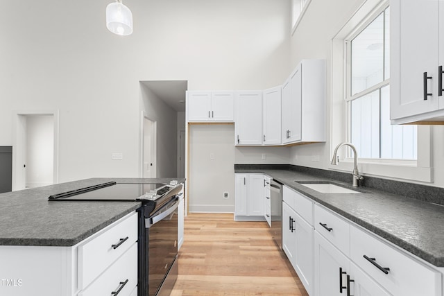 kitchen featuring white cabinets, stainless steel appliances, decorative light fixtures, and sink