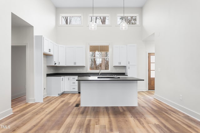 kitchen with decorative light fixtures, white cabinetry, and a high ceiling