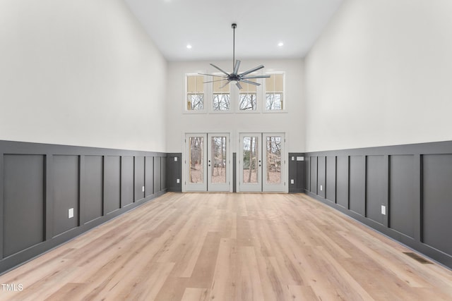 interior space featuring light hardwood / wood-style floors, a towering ceiling, and ceiling fan