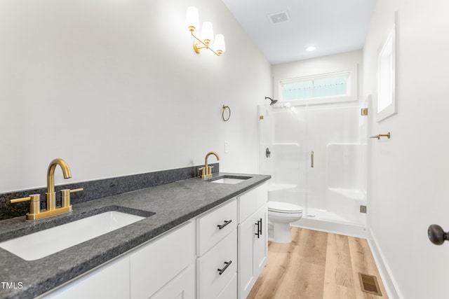 bathroom with hardwood / wood-style floors, toilet, walk in shower, and vanity