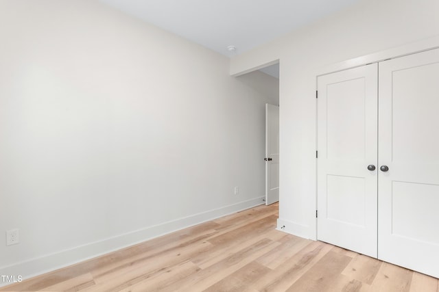 unfurnished bedroom with light wood-type flooring and a closet