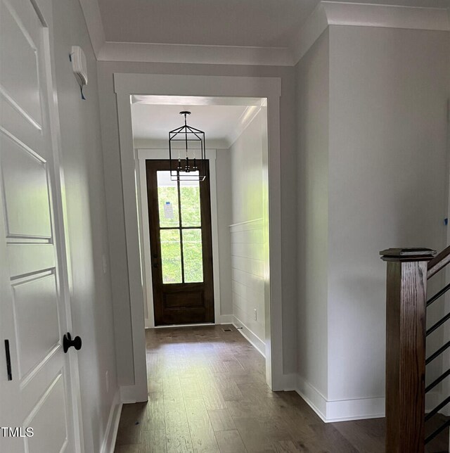 entryway featuring an inviting chandelier, crown molding, and dark hardwood / wood-style flooring