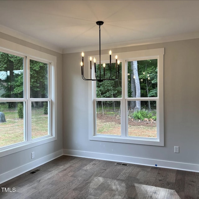 unfurnished dining area with dark wood-type flooring, a wealth of natural light, and an inviting chandelier