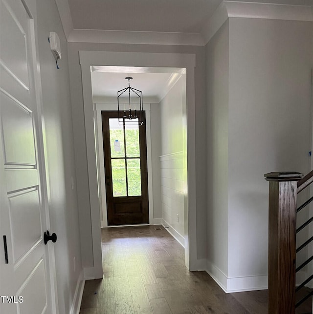 entrance foyer featuring baseboards, an inviting chandelier, wood finished floors, and crown molding