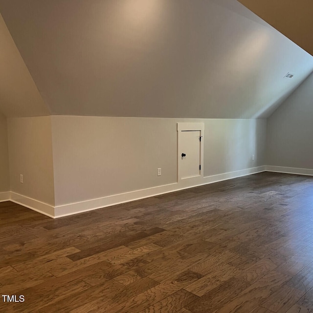 bonus room with dark wood-type flooring, visible vents, baseboards, and lofted ceiling