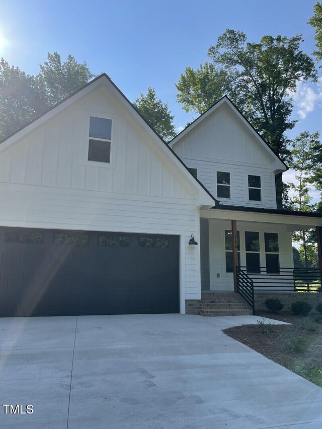 view of front of property with covered porch, board and batten siding, driveway, and a garage