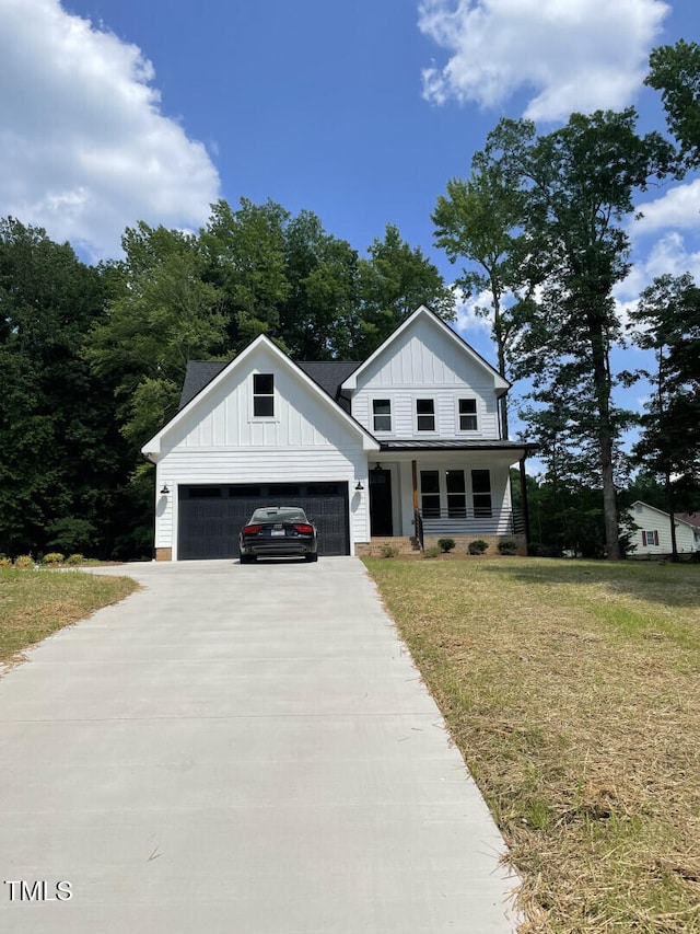 modern farmhouse with driveway, a porch, an attached garage, a front lawn, and board and batten siding