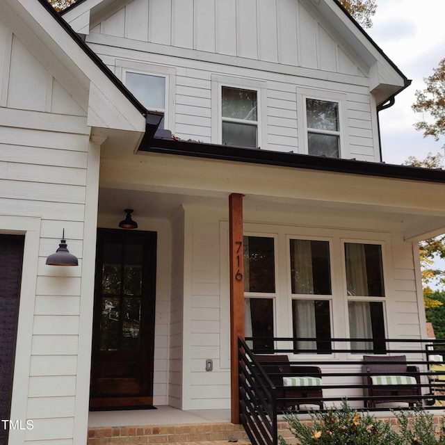 view of exterior entry with covered porch and board and batten siding