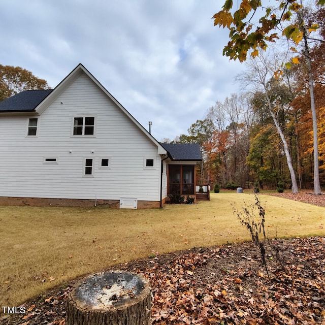 view of side of home with a shingled roof, a yard, and a sunroom
