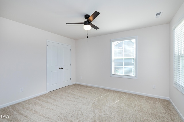 carpeted spare room featuring plenty of natural light and ceiling fan