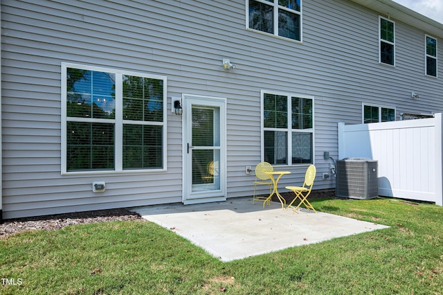 rear view of house with cooling unit, a patio area, and a lawn