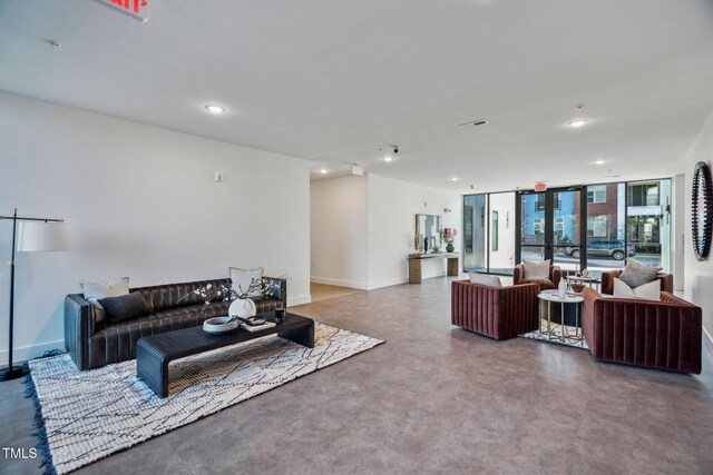 living room with a wall of windows, recessed lighting, baseboards, and concrete floors