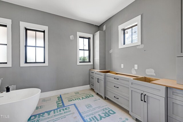 6509 Zebulon Rd, Wake Forest, NC 27587 - bathroom with healthy amount of natural light, a freestanding tub, double vanity, and baseboards