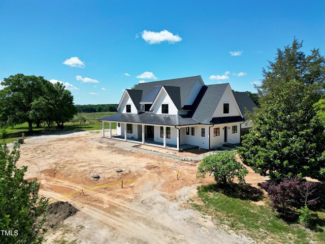 6509 Zebulon Rd, Wake Forest, NC 27587 - modern farmhouse style home featuring dirt driveway, a porch, metal roof, and a standing seam roof