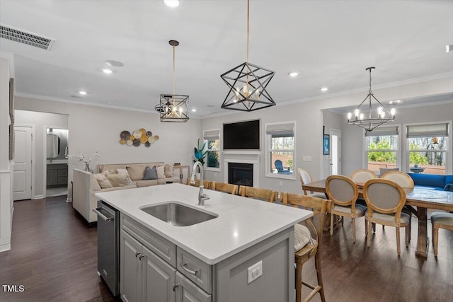 kitchen with pendant lighting, sink, a breakfast bar area, gray cabinetry, and a center island with sink