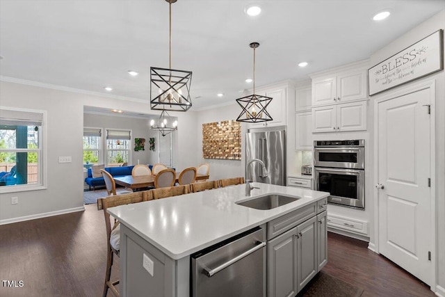 kitchen featuring sink, decorative light fixtures, a center island with sink, stainless steel appliances, and white cabinets