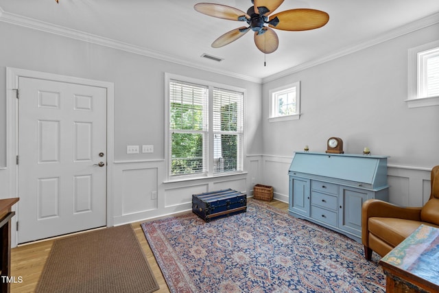 living area with ornamental molding, light hardwood / wood-style floors, and ceiling fan