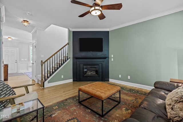 living room featuring hardwood / wood-style flooring, ceiling fan, and ornamental molding