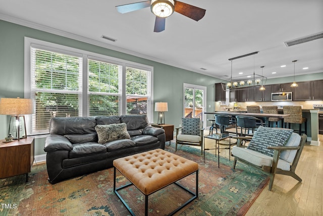 living room with ornamental molding, ceiling fan, and light hardwood / wood-style flooring