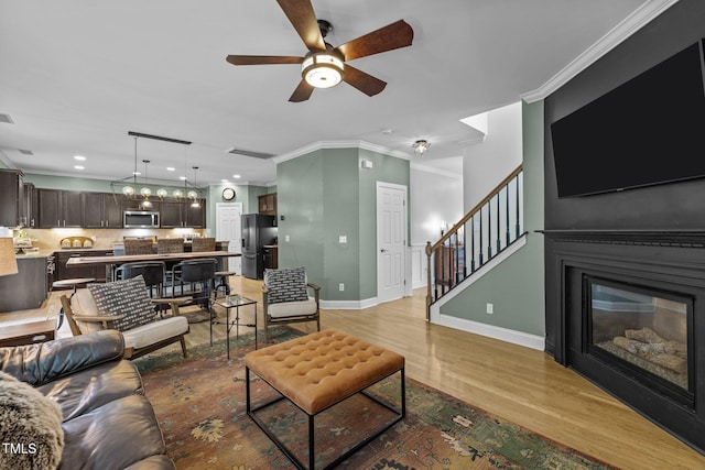 living room with crown molding, ceiling fan, and light hardwood / wood-style flooring