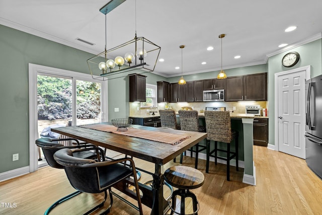 dining room with crown molding and light hardwood / wood-style flooring