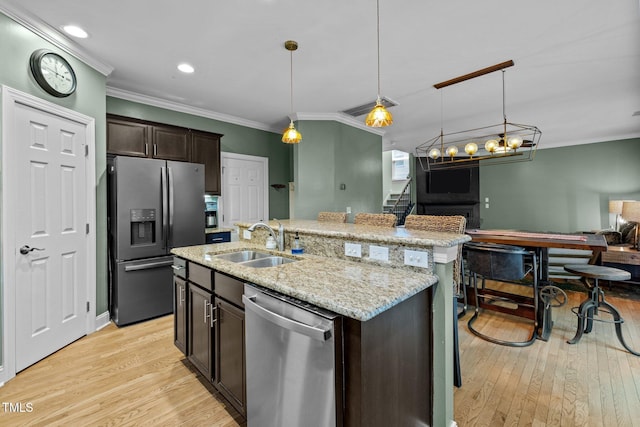 kitchen featuring dark brown cabinetry, sink, hanging light fixtures, a center island with sink, and appliances with stainless steel finishes