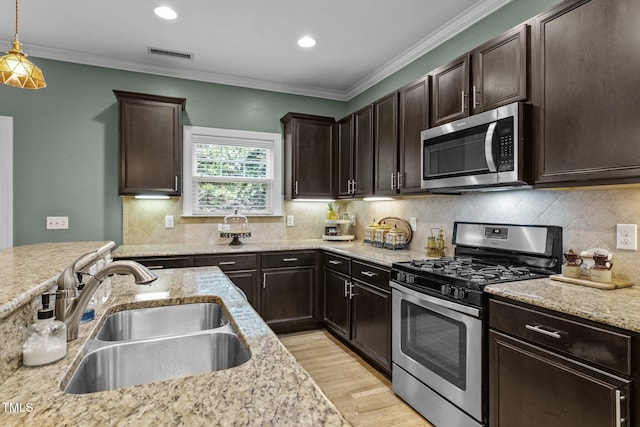 kitchen featuring decorative light fixtures, sink, ornamental molding, stainless steel appliances, and dark brown cabinets