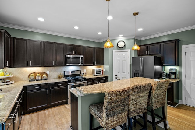 kitchen with stainless steel appliances, pendant lighting, a center island, and a breakfast bar area