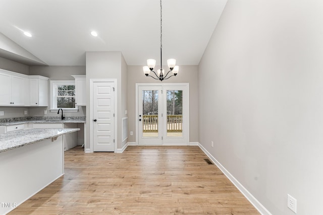 kitchen featuring white cabinetry, light stone countertops, a wealth of natural light, and a chandelier