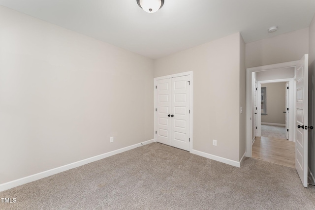 unfurnished bedroom with light colored carpet and a closet