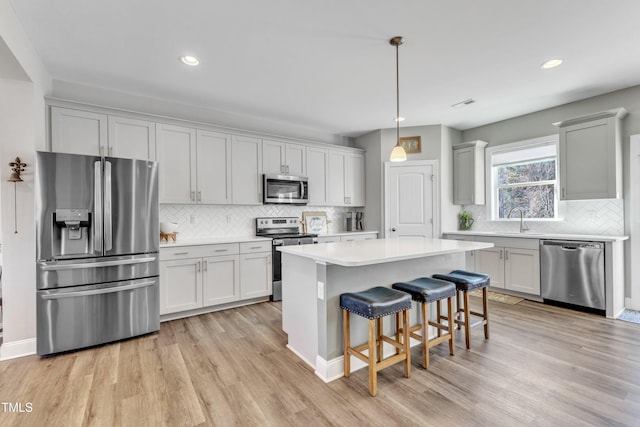 kitchen featuring pendant lighting, sink, a kitchen bar, a kitchen island, and stainless steel appliances