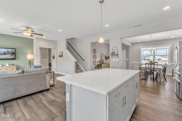 kitchen with a kitchen island, light wood-type flooring, decorative light fixtures, and white cabinetry