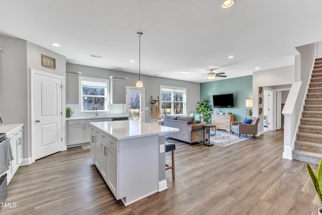 kitchen featuring pendant lighting, sink, light wood-type flooring, white cabinetry, and a kitchen island