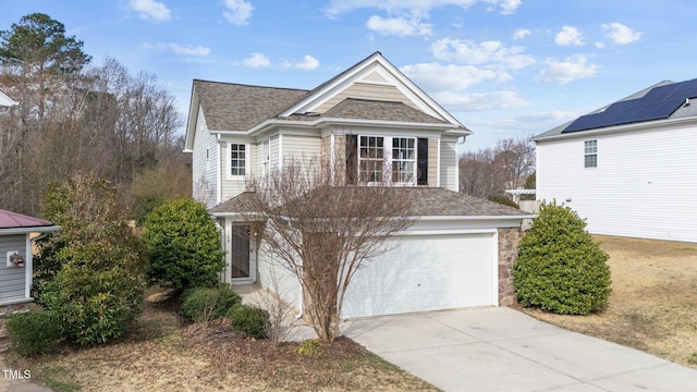 traditional-style house with a shingled roof, stone siding, driveway, and an attached garage